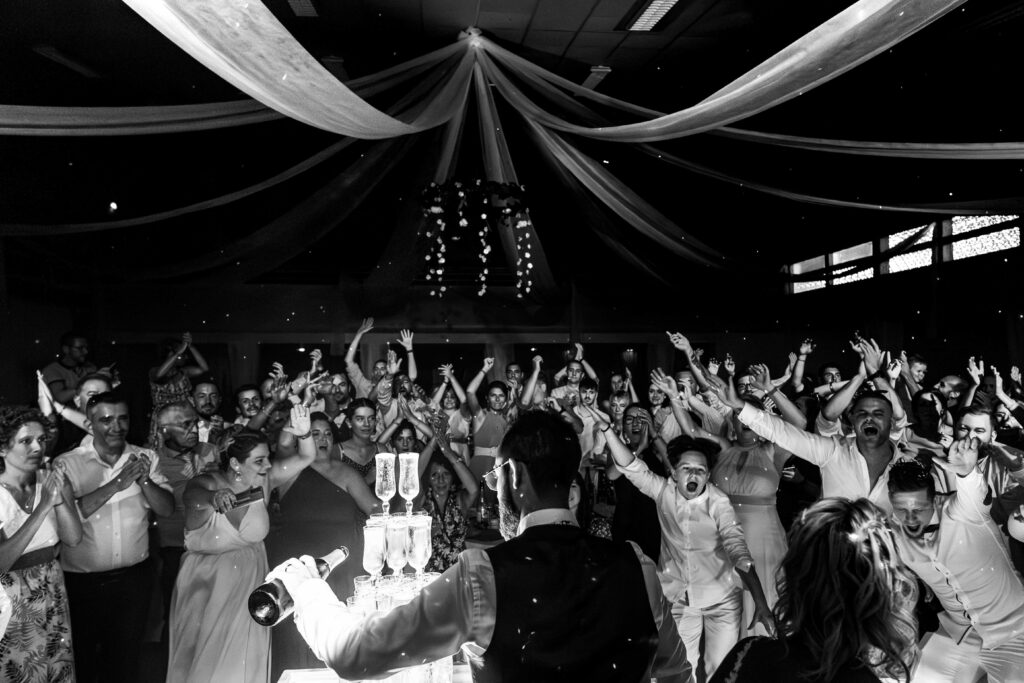 photo ultra fun en noir et blanc des invités surexcités pendant la fontaine de champagne en Deux Sèvres